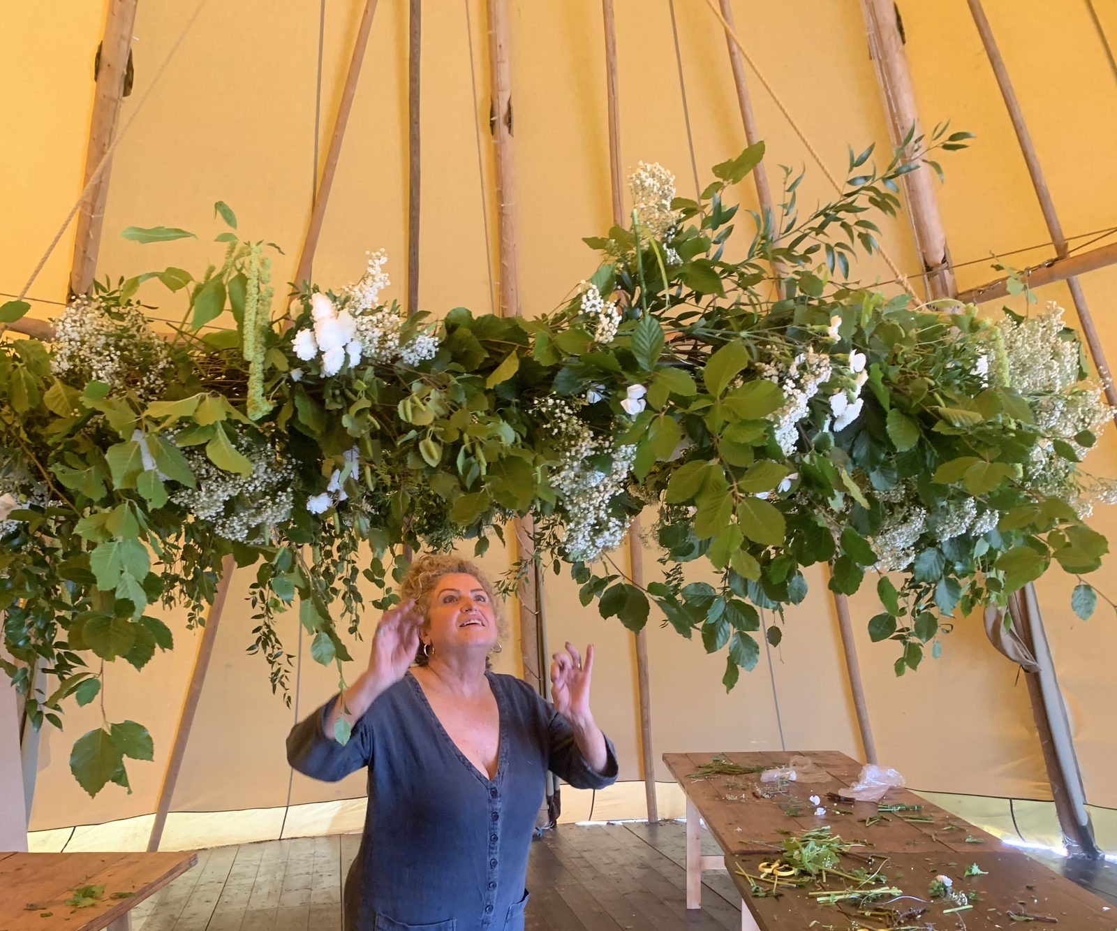 A large hanging floral and greenery installation inside a tipi