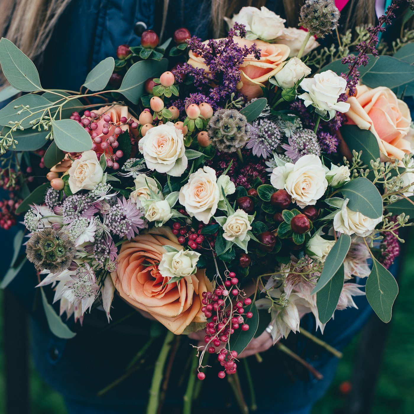 A lush, romantic bouquet of roses, berries and eucalyptus in soft light